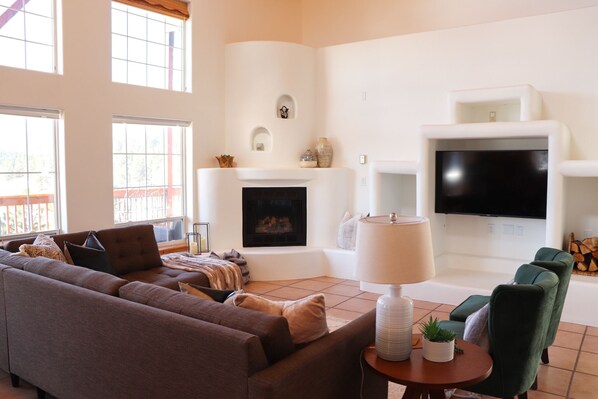 Living area main floor with a smart tv and plenty of seating and the view of the mountains on the windows. 