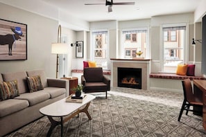 Living room features a sleeper sofa, fireplace, small desk, and flat-screen TV.