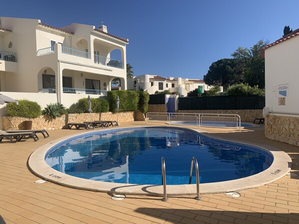 Pool area with sun beds, umbrellas and children’s pool.