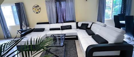 Living room- Large Leather Sofa, Centre Piece, 55 inch Samsung Tv, Plants.