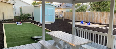 Large patio/ deck features a charcoal barbecue and picnic table.