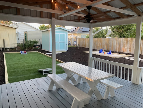 Large patio/ deck features a charcoal barbecue and picnic table.