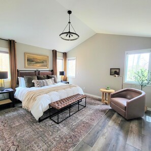 The primary bedroom features a king-sized bed, chair, and 48" TV. 