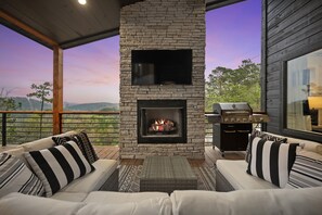 Cozy Corner: Indulge in relaxation on plush outdoor seating, warmed by a glowing fireplace, offering a seamless blend of comfort and the great outdoors. 