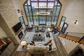  Lofty Serenity: A soaring view where chic design meets the tranquility of nature, crowned by a striking chandelier that illuminates your evenings with warmth. 