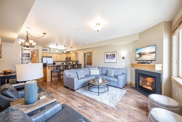 The living area features a comfortable L shaped sectional sofa, a flat screen HDTV, a gas fireplace.