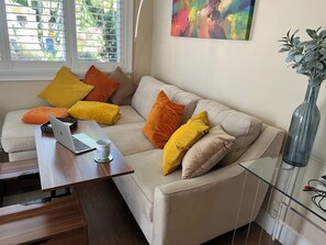Den with a view of the tropical backyard and the couch facing a Smart TV