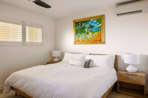 Master bedroom with a king sized bed and memory foam hybrid mattress. Sonos speaker. AC. Writing desk. Original Hawaiian art depicting a Hawaiian wedding.