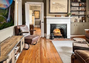 Living room with a comfy sectional sofa, bar area with glassware and bar accessories, and a smart tv.