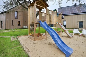 An outdoor playground with a blue slide and a wooden climbing structure, perfect for children.