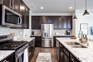 Full kitchen with stainless steel appliances, a gas stove, and all of the cooking utensils you could need to cook three meals a day.(Cary, North Carolina executive furnished rental)