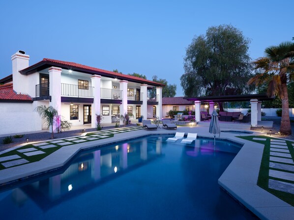 Resort-style backyard with sparkling heated pool & spa, sun loungers, BBQ grill, covered gazebo with multiple lounge areas, outdoor seating, and putting green setup.