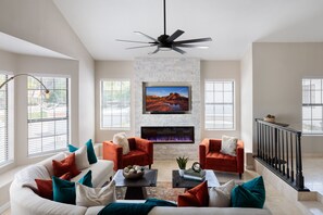 Bright, open-floor formal living space features a smart flat-screen TV, designer furnishings, and an electric fireplace. (1st Floor)