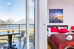 Bedroom corner with a large window and a scenic view, complemented by a cozy red bed.
