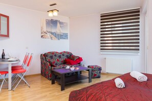 Relaxing living area with a sofa, dining table, and vibrant red decor creating a welcoming space.
