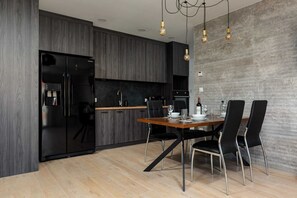 A sleek dining area connected to a modern kitchen with dark cabinets and minimalist décor.