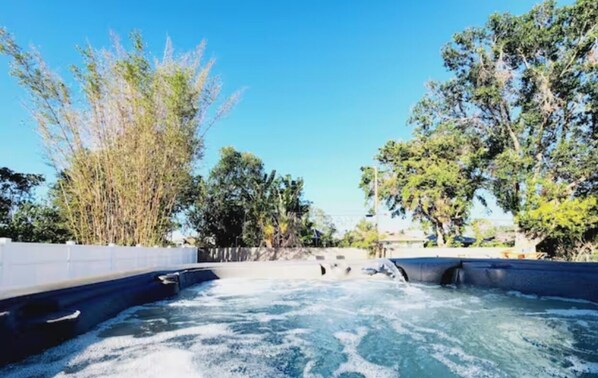 Backyard with hot tub, barbecue grill, outdoor table and chair. 