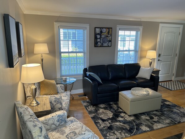 Living room with full-size leather sofa, 2 accent chairs, gas fireplace, and TV.