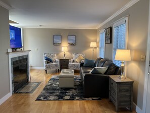 Living room with full-size leather sofa, 2 accent chairs, gas fireplace, and TV.