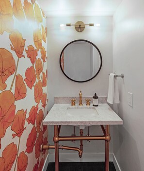 Powder room with marble vanity + brass faucet and fixtures.