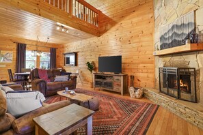 Cozy living room with wood burning fireplace, recliner sofas, and roku TV