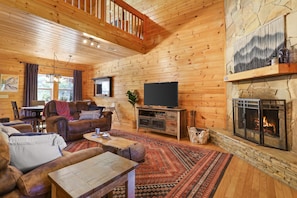 Cozy living room with wood burning fireplace, recliner sofas, and roku TV