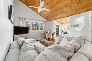 The living area is equipped with a TV for entertainment, a ceiling fan, and comfortable sofa furniture.