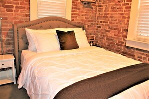 The soaring ceilings create a sense of grandeur, while the exposed brick adds character and warmth to the space. Relax and unwind in the spacious and thoughtfully designed bedroom, surrounded by a harmonious blend of sleek furnishings and rustic textures.