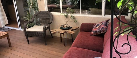 Outside living space includes a couch, teak patio table and feels like an oasis