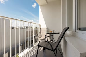 A balcony with a small table and two chairs, offering a relaxing spot with an open view of the sky and surroundings.