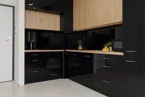 A stylish kitchen in black and wood tones, equipped with modern appliances and a minimalistic design.

