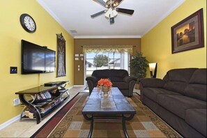 Cozy living room with comfortable seating, a large TV, and ample natural light.