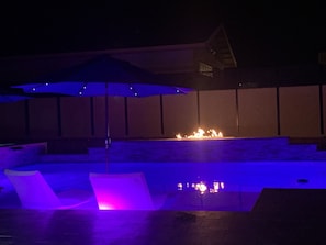 Pool at night with colored lights and fire/water feature.