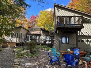 View of the back of the home, the guest house, the fire pit, and the hot tub