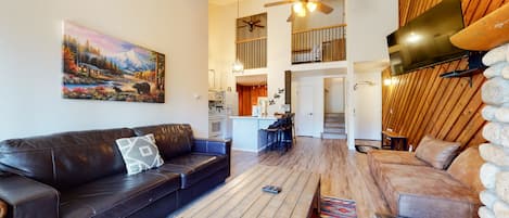 Open living space with sofa, sleeper, TV, fireplace, and balcony