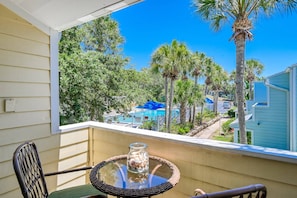 Two balconies offer pool views through palm foliage.