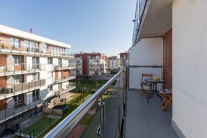 A balcony view showing the building's exterior and neighboring buildings, with a railing and outdoor space.