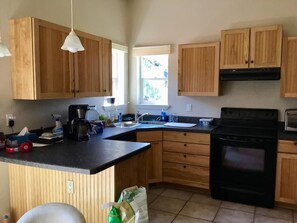 Full kitchen with refrigerator, stove, dish, utensils, etc.