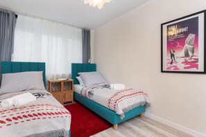 A bedroom with two single beds featuring colorful turquoise and pink bedding, with a modern framed artwork on the wall.
