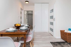 A dining area with a wooden table, chairs, and a stylish open layout connected to the living room. The space has framed artwork and modern furniture.