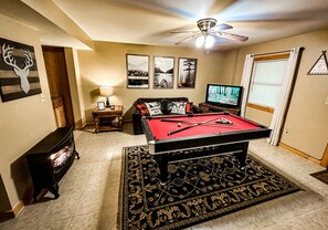 Basement with pool table, sofa bed, and gas fireplace