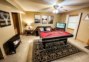 Basement with pool table, sofa bed, and gas fireplace