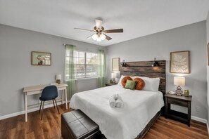 The generous master bedroom with a queen bed and stylish workspace