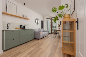A kitchen with green cabinets, a modern stove, and open wooden shelves for a clean and stylish look.