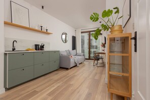A kitchen with green cabinets, a modern stove, and open wooden shelves for a clean and stylish look.