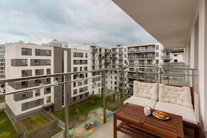A view from the balcony showing the surrounding apartment complex with greenery and a courtyard below.