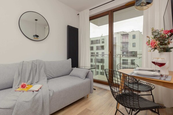 A living room featuring a cozy gray sofa, a small round coffee table, and large windows providing ample natural light and a view outside.