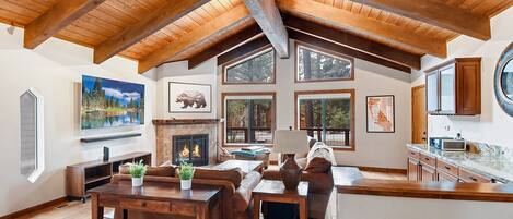 Large open living space with TV, fireplace, and deck access