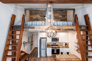 Cozy retreat with 2 queen loft beds, dining area, and kitchenette.