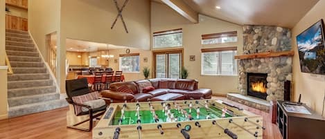Open living space with Smart TV, foosball table, gas fireplace, and deck access